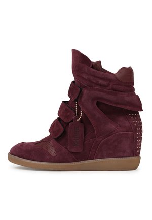 Sneaker zeppa in camoscio bordeaux con cinturini in velcro, colletto imbottito alla caviglia, suola in gomma, tacco borchiato e etichetta in camoscio con marchio appesa al lato.