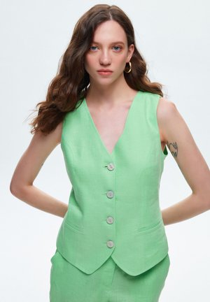 Gilet en lin vert avec un décolleté en V profond, cinq boutons et des poches latérales. Présente une texture lisse et un design ajusté.