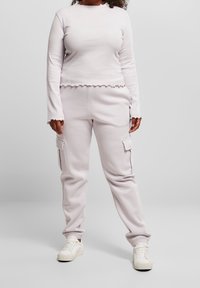 Lila långärmad topp med volangkant och matchande cargo-byxor med sidofickor, tillsammans med vita sneakers. Material av bomullsblandning.