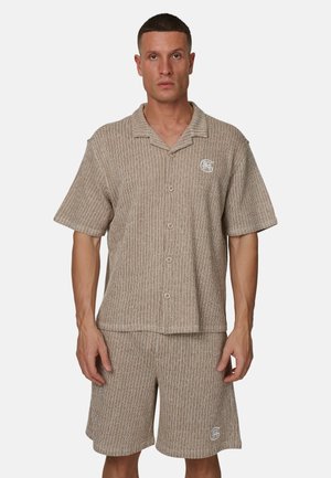 Jasnobrązowy dzianinowy dwuczęściowy zestaw składający się z koszuli z krótkim rękawem, kołnierzykiem i zapięciem na guziki oraz dopasowanych szortów.