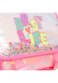 Sac à dos transparent avec un cadre rose, face avant transparente, lettrage coloré « BEST LIFE » et rempli de confettis et de vermicelles au fond.