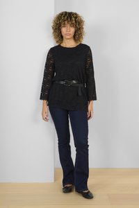 Black lace top with bell sleeves, scalloped hem, paired with dark blue flared jeans and black flats. Simple belt accents the waist.