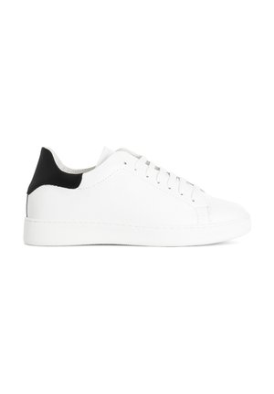Baskets en cuir blanc avec une finition texturée, patin noir au talon, semelle plate et design à lacets à six œillets. Simple et minimaliste.