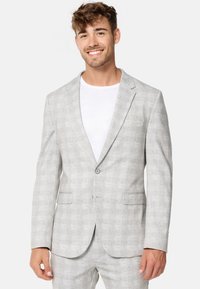 Sacou gri deschis cu un model subtile de carouri, închidere cu un singur nasture, rever cu decupaj și două buzunare frontale. Purtați peste un tricou alb.
