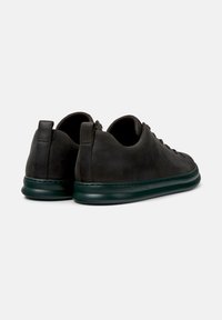 Gray suede sneakers with a dark green sole, viewed from the back, showcasing the smooth texture and minimalist design.