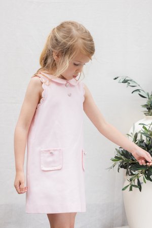 Rožinės spalvos ilgai nepatenkintas su tekstūruotu audiniu, banguotu apykakliu, dviem priekinėmis kišenėmis ir dekoratyviniais mygtukais. Detalės apima minkštą paviršių.