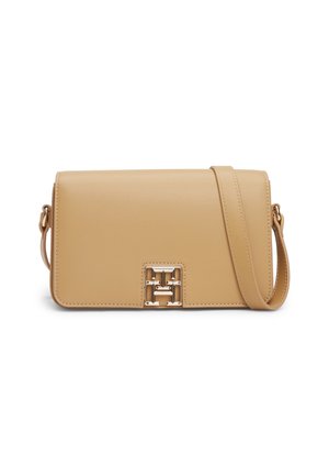 Lichtbruine leren crossbody tas met klepsluiting en een goudkleurige decoratieve gesp aan de voorkant.