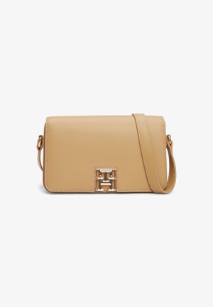 Lichtbruine leren crossbody tas met klepsluiting en een goudkleurige decoratieve gesp aan de voorkant.