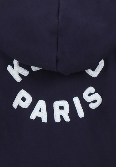 Felpa navy con cappuccio caratterizzata da un morbido ricamo bianco con la scritta "KIDS PARIS" sulla parte posteriore, dotata di cappuccio rotondo e tessuto di texture soffice.