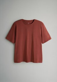 Kortärmad t-shirt i rostfärgad, slät bomullstyg. Har en rund halsringning och en avslappnad passform, utan synliga mönster eller detaljer.