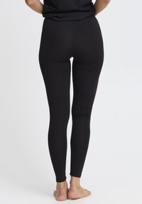 Juodos tamprės pagamintos iš lygaus, tampraus audinio. Aptemptos, su aukštu liemeniu ir pilno ilgio kojomis. Be matomų raštų ar papuošimų.