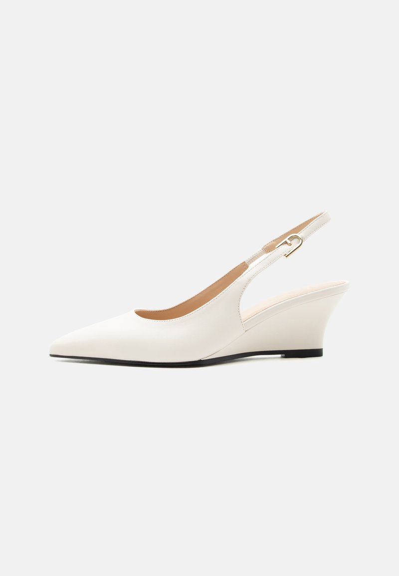 Chaussure compensée blanche à bride arrière avec bout pointu et petite boucle dorée sur la bride de cheville réglable, présentée sur un fond clair uni.