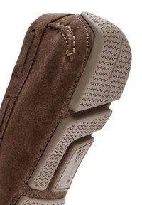 Zapato de ante marrón con una suela texturizada, que presenta un patrón en zigzag y un detalle de costura en el lateral, diseñado para la comodidad y la durabilidad.