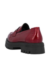 Chaussure en cuir verni rouge à enfiler avec une semelle en caoutchouc noir épaisse et un talon texturé. Dotée d'un bout rond et d'un détail de logo discret sur le côté.
