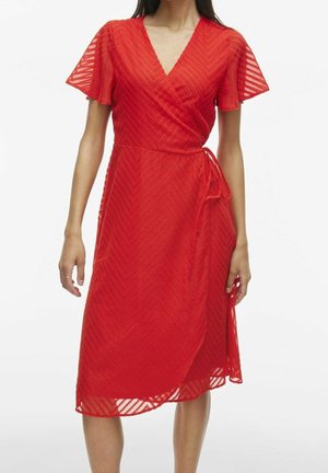 Rotes Wickelkleid mit Chevron-Struktur, kurzen Volantärmeln, knielang, in der Taille gebunden, getragen von einer stehenden Person vor weißem Hintergrund.
