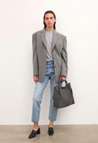 Grå oversized kavaj, ljusgrå tröja, ljusblå raka jeans, svarta loafers, grå toteväska med sidhandtag, släta texturer.
