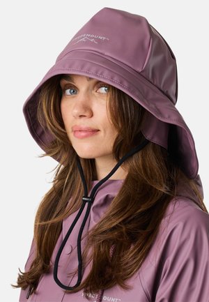 Vrouw met lang bruin haar die een paarse waterdichte capuchonjas met trekkoorden draagt, lichtblauwe ogen en een neutrale uitdrukking.