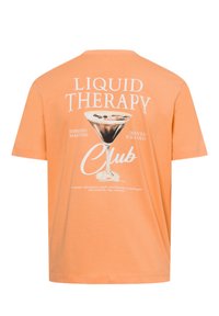 Peach-colored t-shirt with short sleeves. Features a graphic print of a martini glass and text stating "Liquid Therapy" in white.