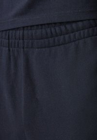 Čierne bavlnené tepláky s elastickým pásom a bočnými švami, ktoré sa vyznačujú jemnou textúrou a hladkým povrchom.