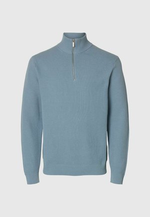 Lichtblauwe gebreide trui met lange mouwen, ribbelmanchetten en -zoom, en een korte rits aan de hoge kraag.