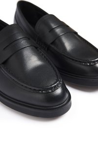 Sorte læder loafers med en rund tå, dekorativ syning og en hævet møntslugningsdetalje på tværs af foden. Mat finish.