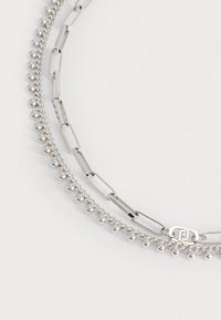 Collana a strati in argento con perle rotonde e anelli allungati, caratterizzata da una texture liscia e dettagli di chiusura.