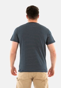 T-shirt rayé bleu marine et blanc en coton, avec des manches courtes et un col rond, porté avec un short en khaki.