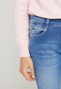 Džíny z denimu s postupným ombré od světlé po tmavou, pěti-kapsový design a stříbrné kování. Vypadají skvěle s měkkým růžovým topem s dlouhým rukávem.