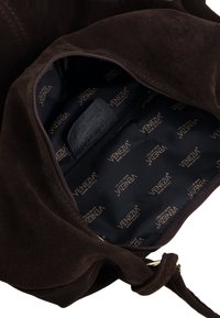 Brun ruskindtaske interiør med sort foring med gentagende "VENEZIA" logo, lynlåslomme bagpå og blød tekstur.