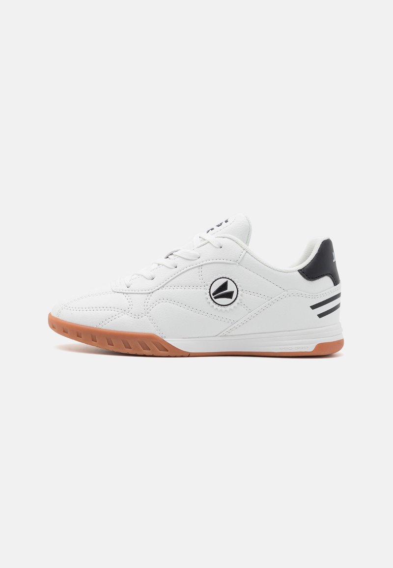 Zapatilla deportiva blanca con parte superior de cuero texturizado, punta redonda, suela de goma y acentos negros en el talón y en el logotipo.