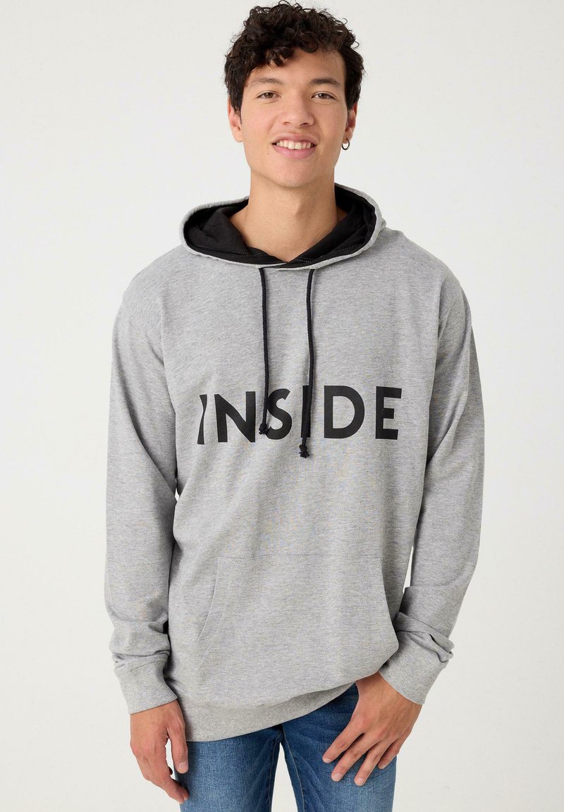 Sudadera gris con cordones negros y gran texto negro "INSIDE" en el frente. Cuenta con un bolsillo tipo canguro y una capucha negra en capas.