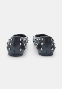 Black leather flats with silver studs embedded on the exterior surface, featuring a round toe and low-profile design. Smooth texture.