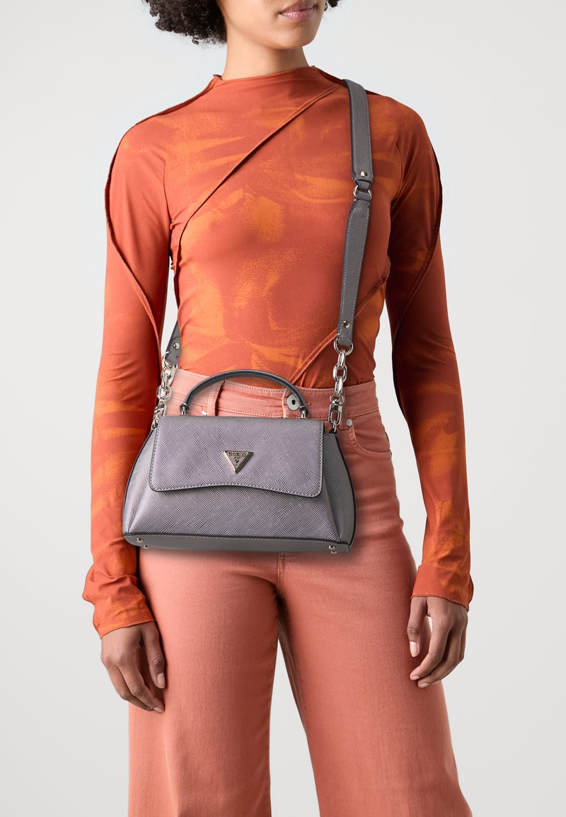 Borsa grigia con una finitura testurizzata, manico superiore e una tracolla staccabile. Presenta un logo triangolare e un design strutturato e contemporaneo.