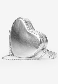 Bolso plateado en forma de corazón, hecho de material metálico con cremallera, correa de cadena y textura suave. Presenta un diseño compacto para el almacenamiento.