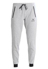 Pantalones de chándal grises con bolsillos con cremallera negra, cinturilla elástica y puños. Presenta un logo en la parte frontal. Fabricado en material suave y cómodo.
