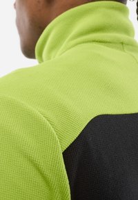 Fleece collar sweatshirt in vibrant lime green with a textured finish, featuring a contrasting black panel. Close-up of shoulder detail.