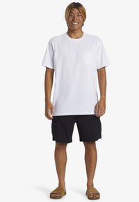 White short-sleeve T-shirt with a chest pocket, paired with black cargo shorts and brown slide sandals. Simple design, casual fit.