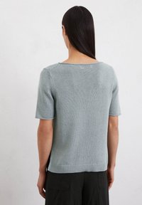 Hellblaues kurzärmliges Sweatshirt mit rundem Halsausschnitt, geripptem Saum und glatter Textur. Die Rückansicht zeigt die Schulternähte und eine lockere Passform.