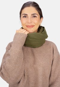 Écharpe vert olive en tissu doux, enroulée autour du cou. Pull marron clair avec poignets côtelés. Design simple et confortable.