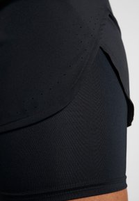 Pantalones cortos deportivos negros confeccionados con una tela suave y elástica, con acentos perforados y un diseño ajustado y elegante. Cuenta con una abertura lateral para mayor movilidad.