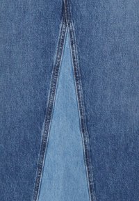 Farmernadrág, alsó részen hasított dizájnnal, kontrasztos világos és sötétkék szövetekkel, látható varrásokkal és puha tapintással.