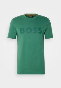 Vihreä puuvillapaita, jossa on pyöreä kaula-aukko, lyhyet hihat ja suuri sävy säilyttävä "BOSS" -logo edessä. Sileä materiaali, rento malli.