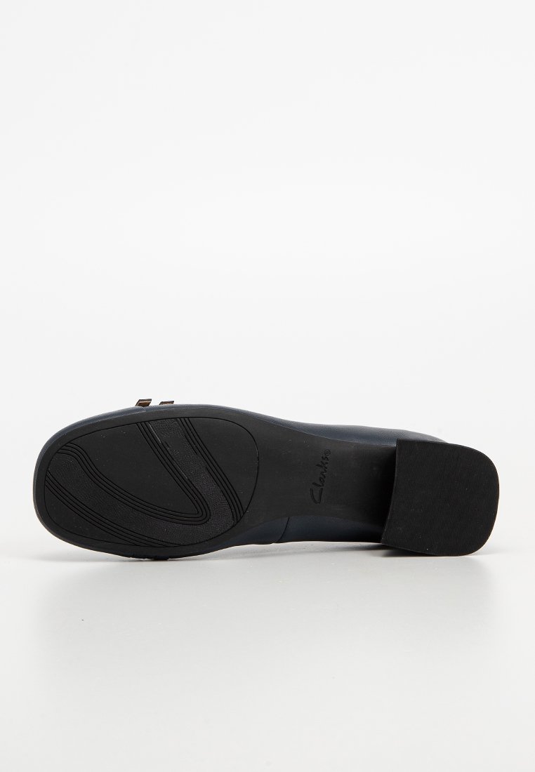 Schwarze Sohle eines Damenschuhs mit Blockabsatz, strukturiertem Griffmuster auf der Vorderseite und "Clarks"-Markenlogo im Bereich des Fußgewölbes.