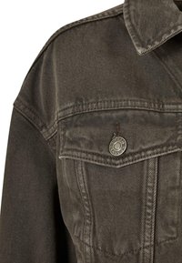 Dark grey denim jacket featuring a button closure, chest pockets, and a pointed collar with textured fabric and stitching details.