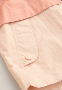 Kortärmad skjorta i ljusrosa och persika, med ett strukturerat rutmönster, en mjuk tygkvalitet och en rund, rosa knapp på fickan.