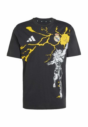 Maglietta nera in cotone con grafica di un fulmine giallo e una figura stampata sul davanti. Include il logo Adidas e l'emblema del Real Madrid.