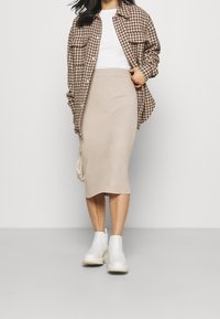 Košile s velkým vzorem houndstooth, oversized saka, ribbovaná béžová sukně, bílé kotníčkové boty a malá krémová kabelka na rameno. Obsahuje texturované materiály.