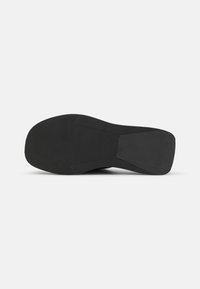 Svart gummisåle med en rippet tekstur, som har en rund form og flat bunn for godt feste. Minimalistisk design uten dekorasjoner.