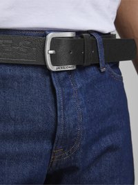 Cinturón de cuero negro texturizado con una hebilla metálica plateada. Presenta el logotipo grabado "JACK&JONES" en la correa, combinado con jeans de denim azul.