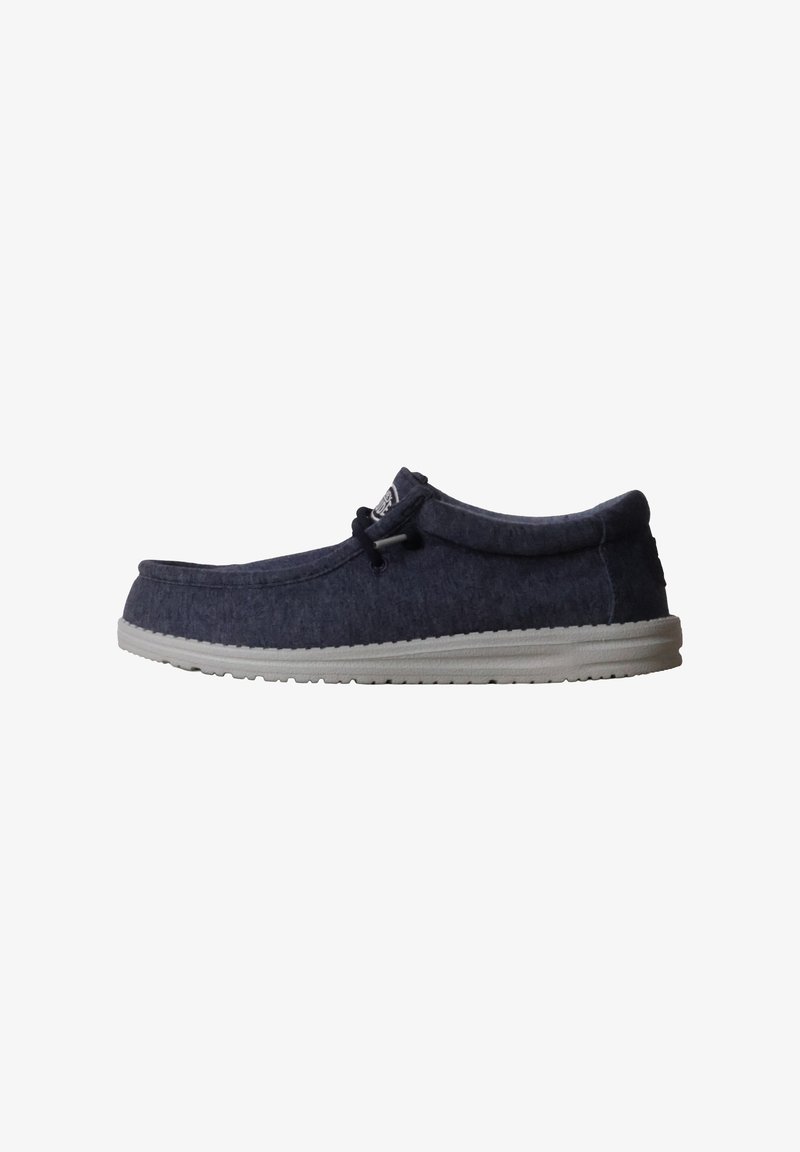 Mocassin décontracté en tissu bleu foncé pour homme, semelle en caoutchouc blanche et détail lacé noir, vu de côté sur fond blanc.